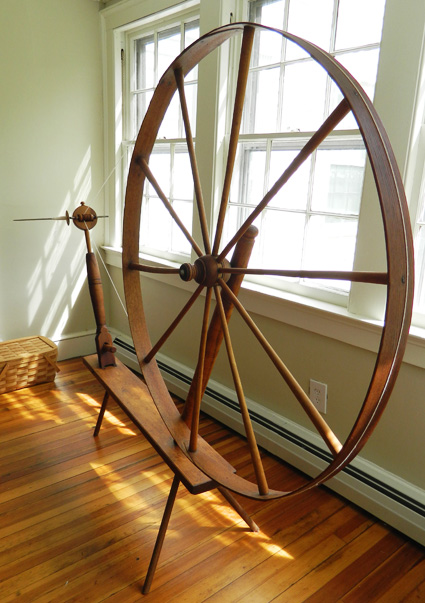 Great wheel for spinning wool or cotton sits in the dappled light of the afternoon